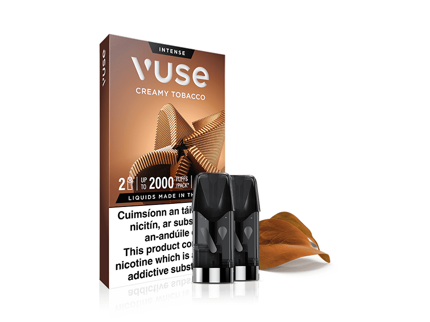 Vuse Ireland A Vuse Creamy Tobacco vape pod pack with two pods in front and a tobacco leaf beside the box. The packaging highlights nicotine content and warnings in English and another language.