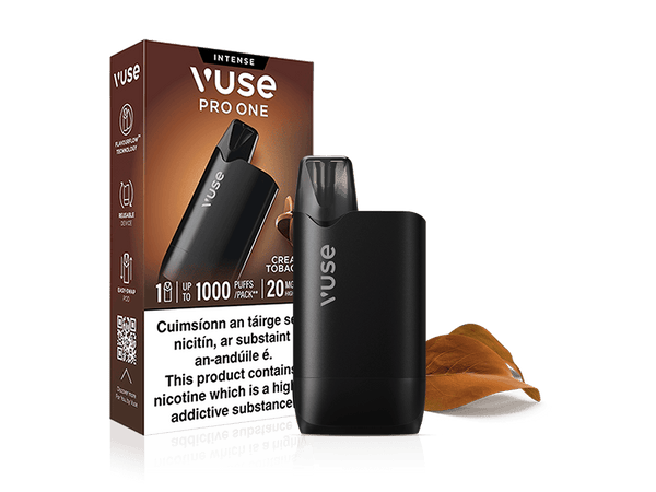 A VUSE Pro One Box Creamy Tobacco rechargeable vape device is positioned in front of its branded packaging, which displays detailed product information. Two brown tobacco leaves are placed next to the device, emphasizing the creamy tobacco flavor of this VUSE Pro One.