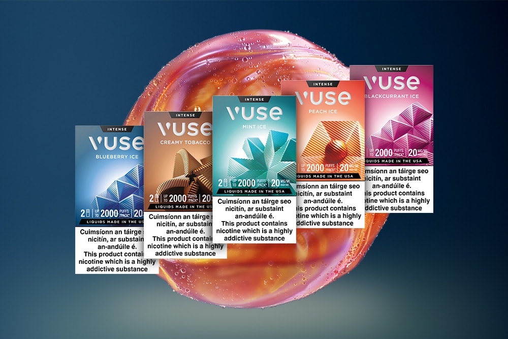 Vuse Ireland Five Vuse vape boxes—Blueberry Ice, Creamy Tobacco, Mint Ice, Peach Ice, and Blackcurrant Ice—are displayed in front of a shiny, abstract sphere, with health warnings about nicotine at the bottom of each box.