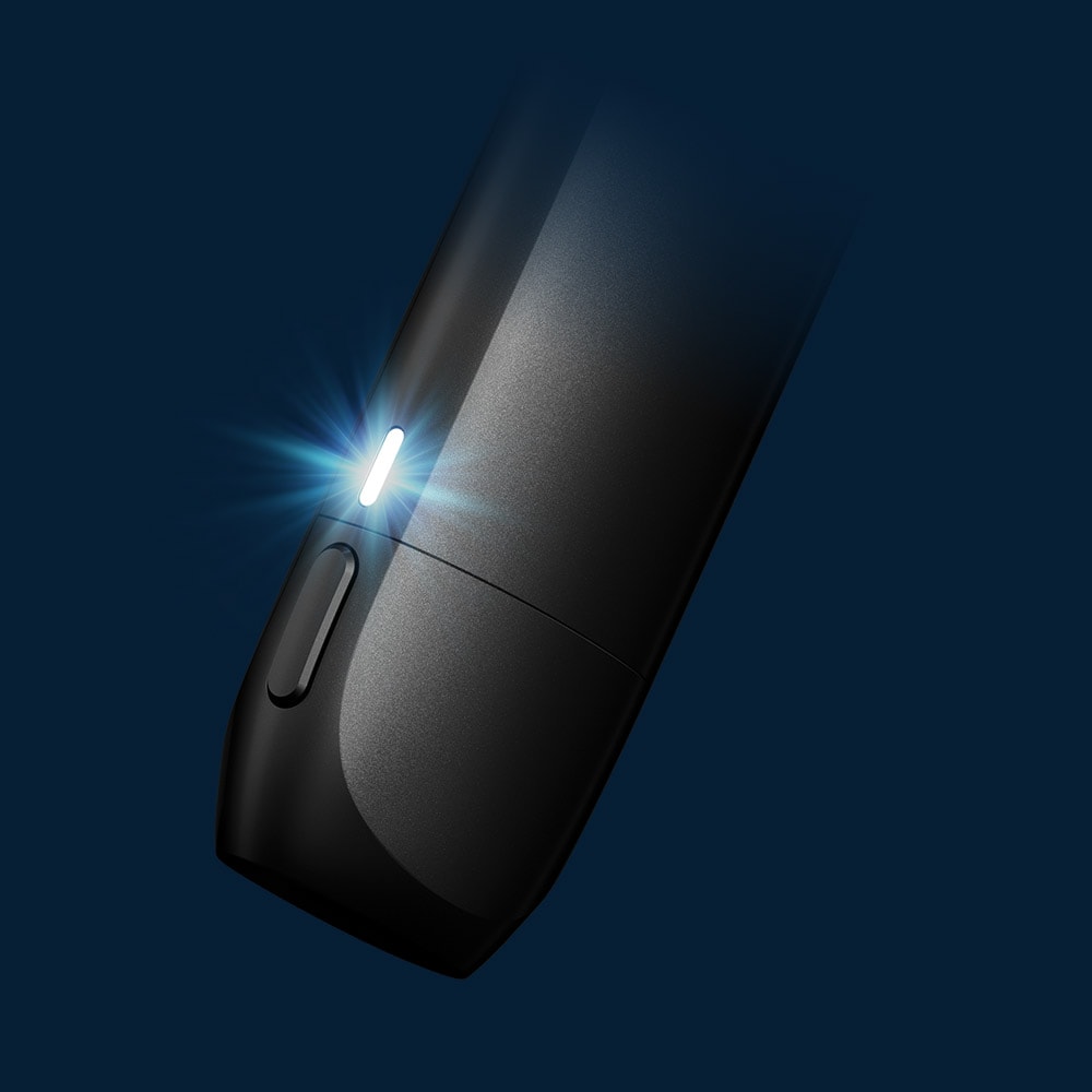 Vuse Ireland Close-up of a sleek black electronic device with a glowing white LED indicator light, set against a dark blue background.