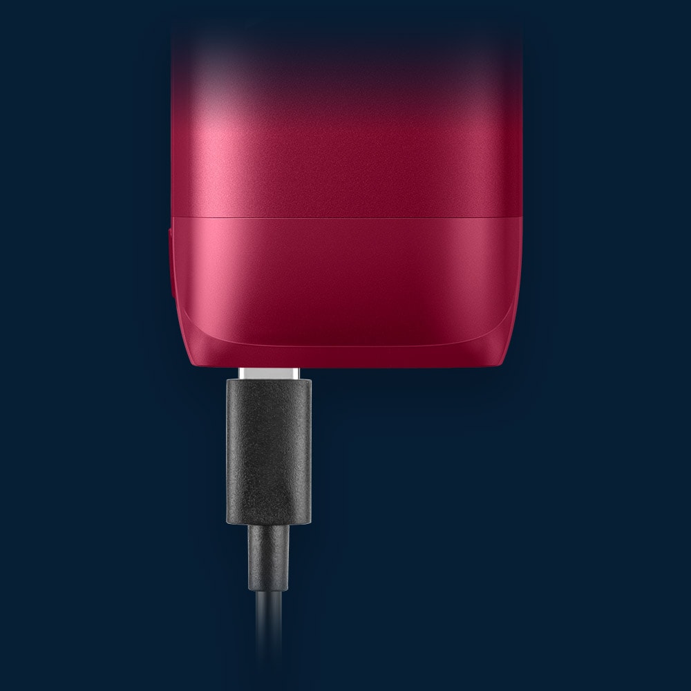 Vuse Ireland A close-up of a black USB-C cable plugged into the bottom of a red electronic device against a dark blue background.
